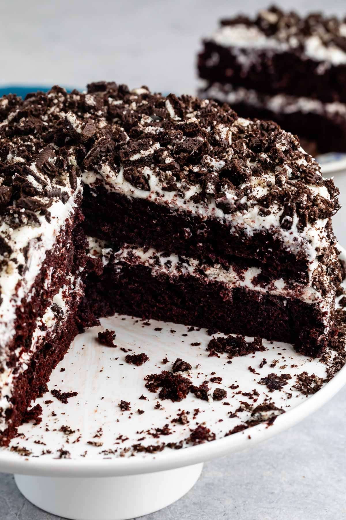 brown layered cake with white frosting and crushed oreos on top.