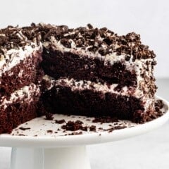 brown layered cake with white frosting and crushed oreos on top.