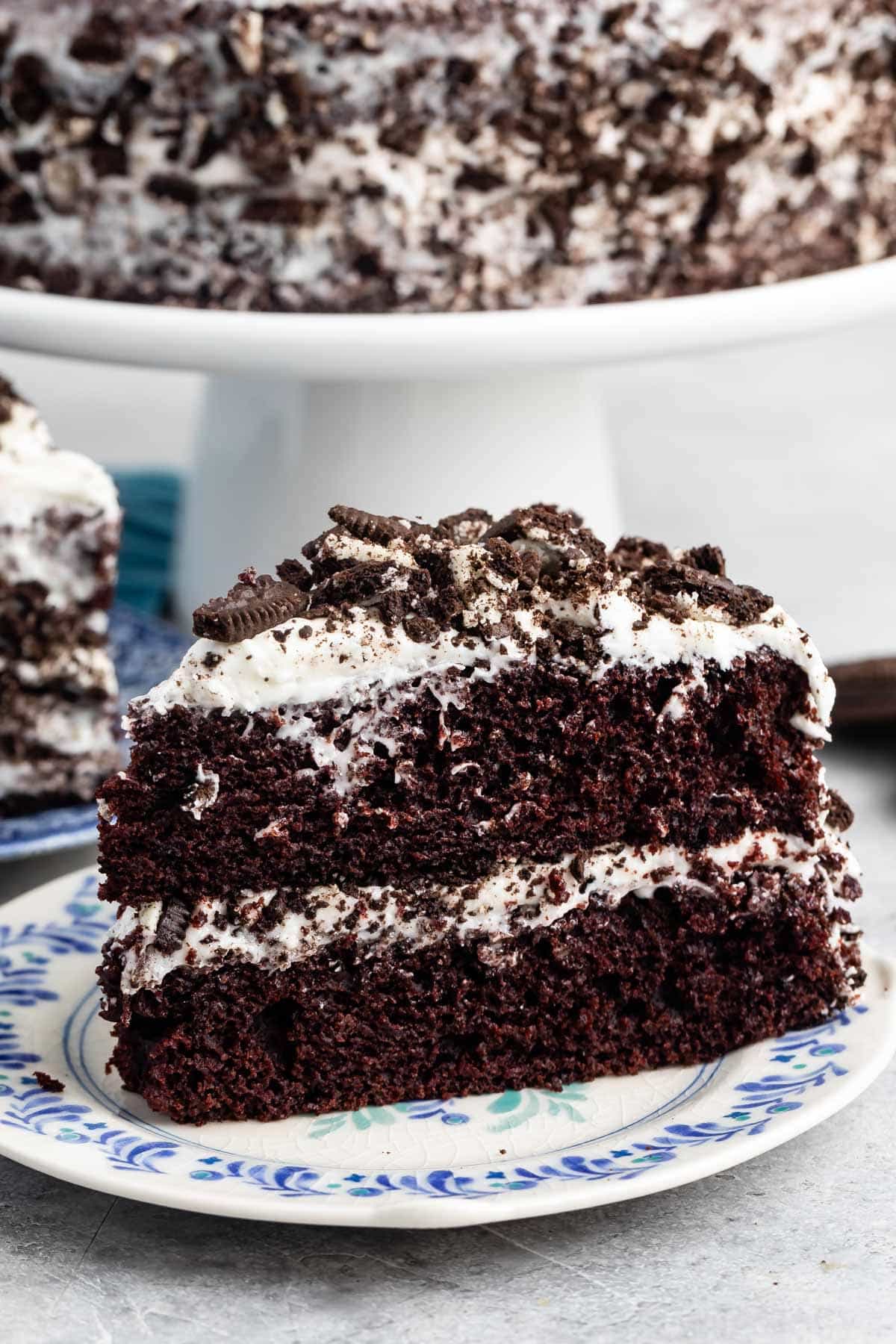 brown layered cake with white frosting and crushed oreos on top.
