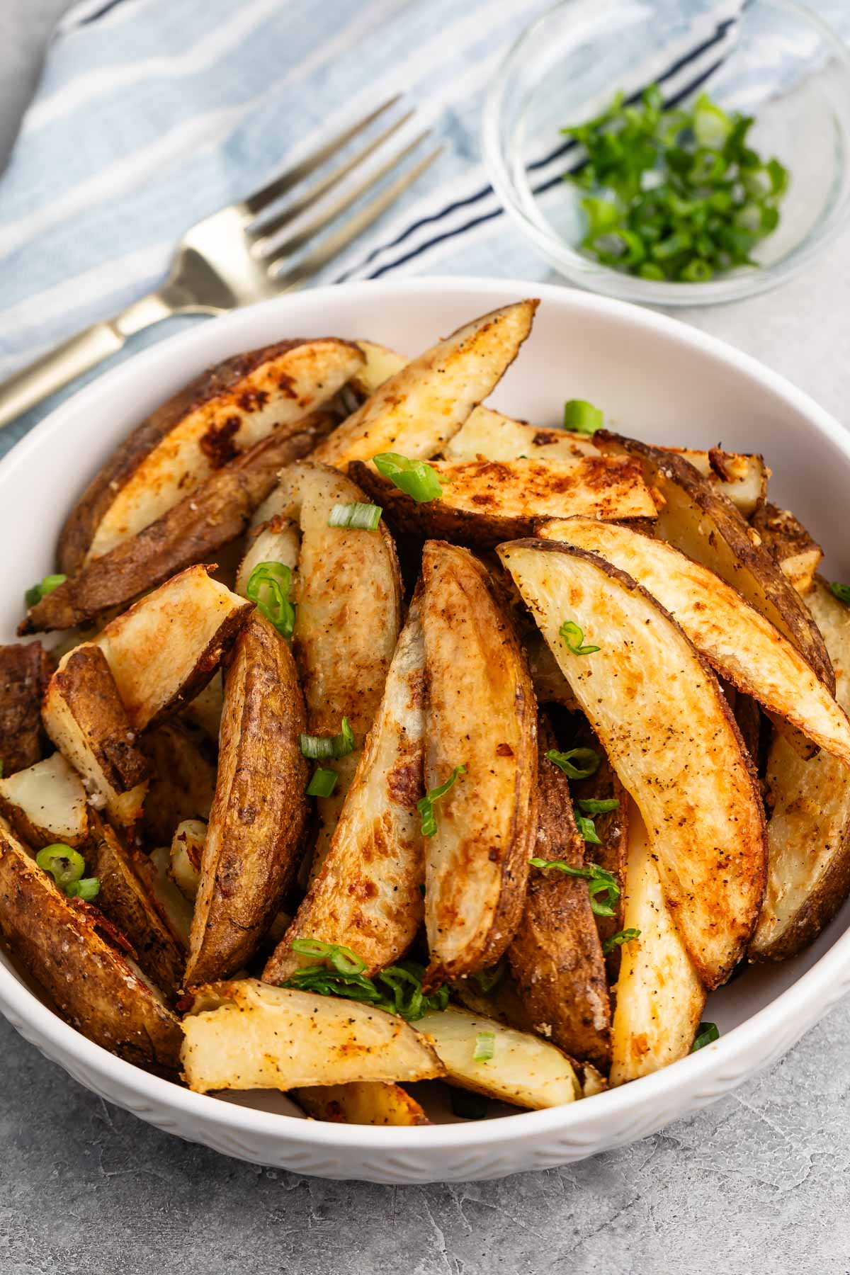 potato wedges in a white bowl with a green garnish.