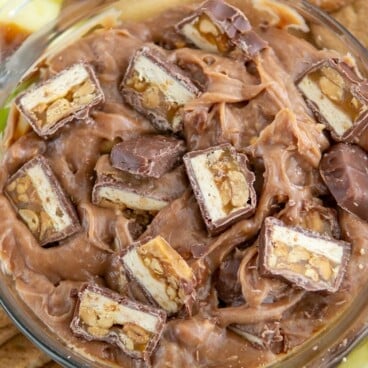 chocolate dip with chopped snickers inside and surrounded by apples.