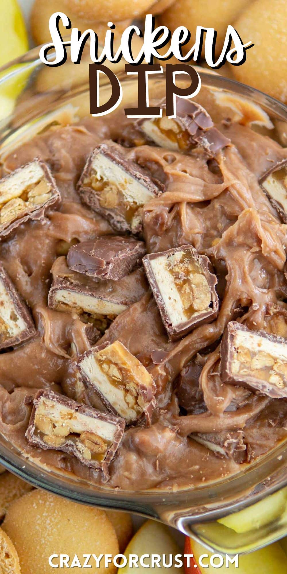 chocolate dip with chopped snickers inside and surrounded by apples with words on the image.