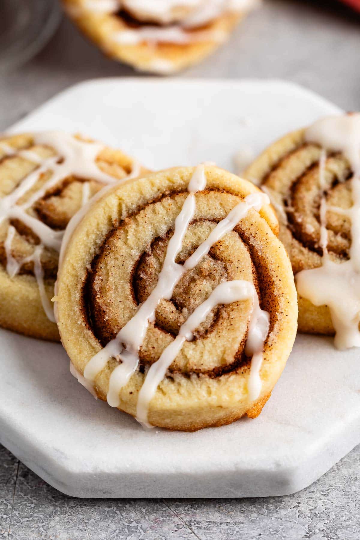 stacked cinnamon roll cookies with a glaze on top.