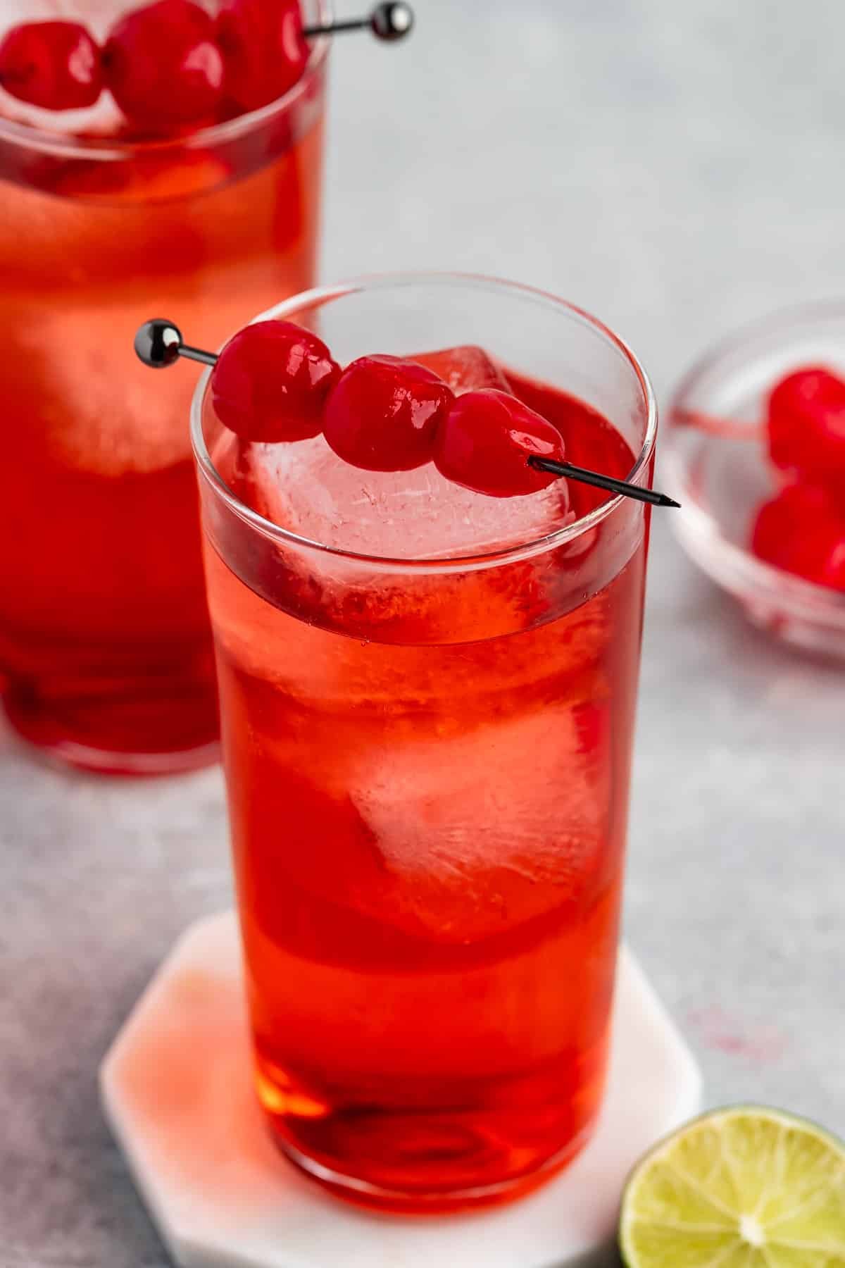 shirley temple in a tall clear glass with cherries along the top.