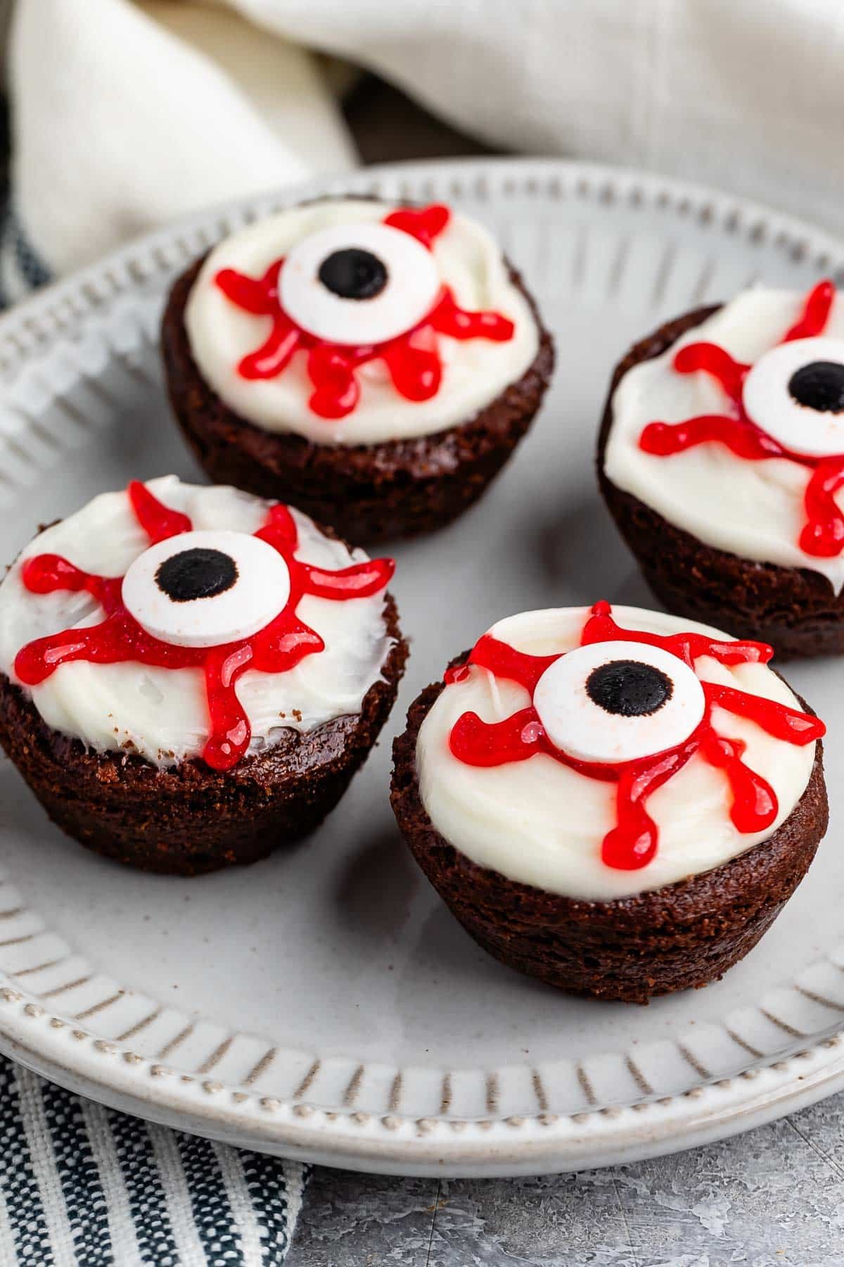 brownies bites with a white frosting, red gel, and candy eyeball on top.