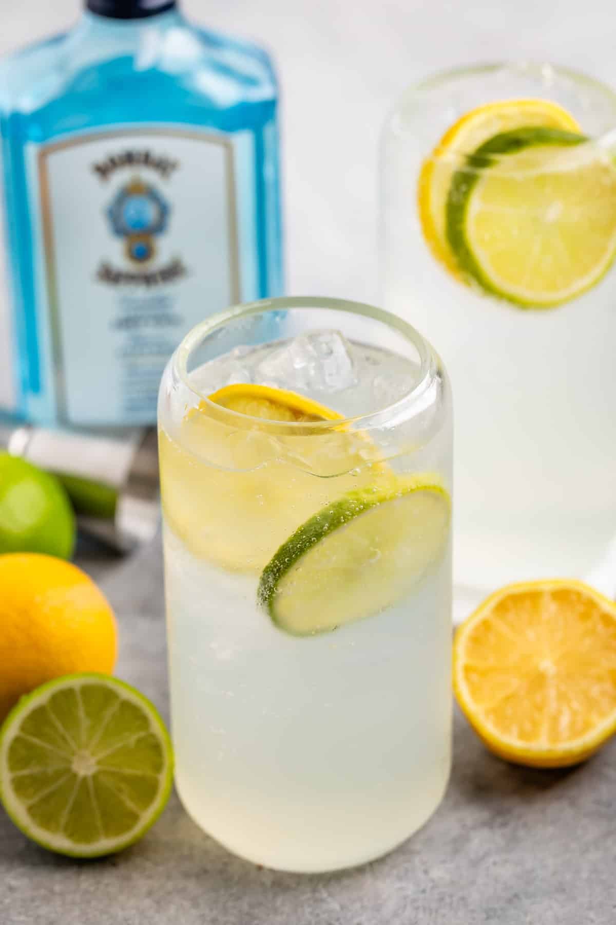 glass cup with clear drink inside and with sliced lemons and limes inside.