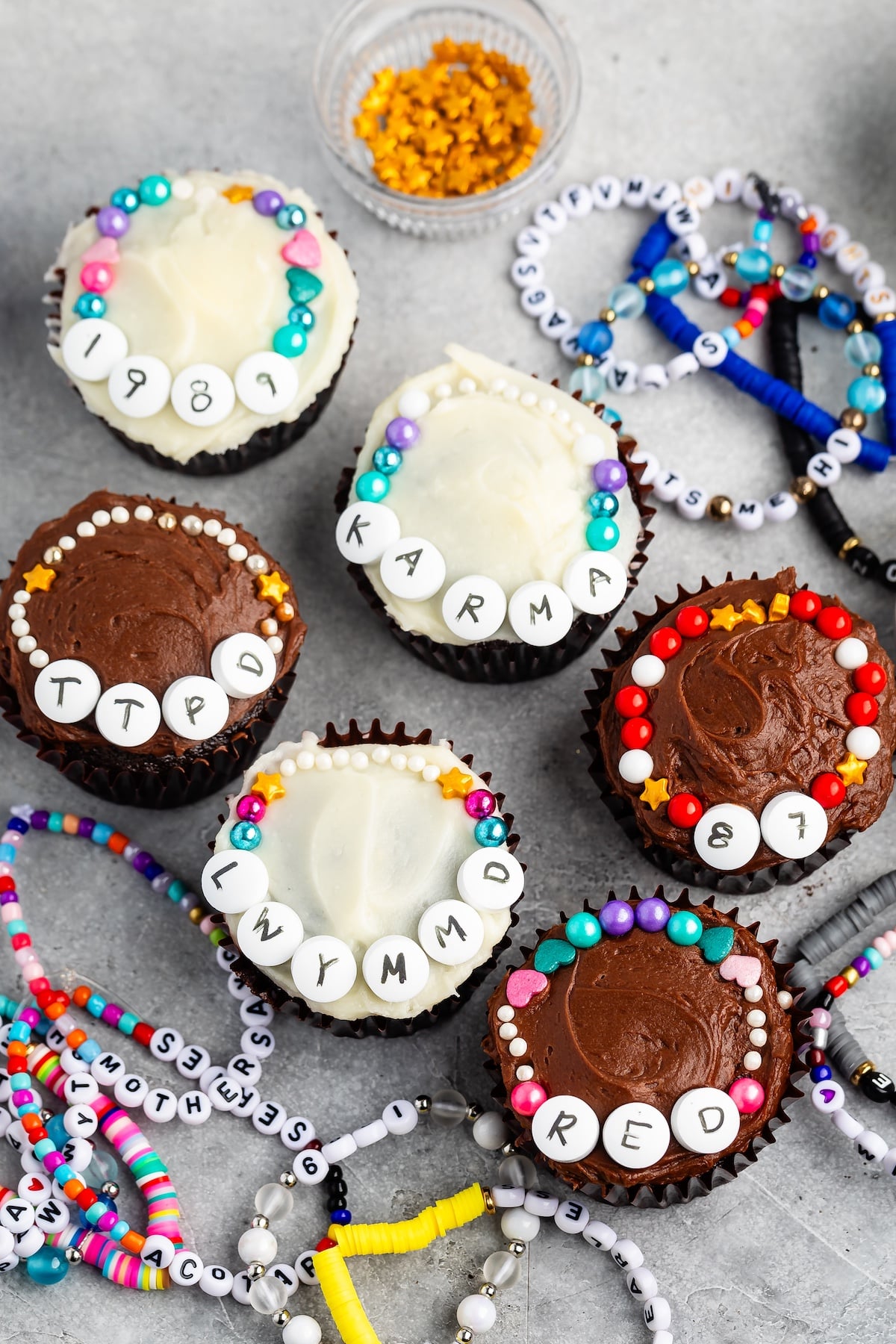 cupcakes with white and chocolate frosting decorated with candy friendship bracelets.