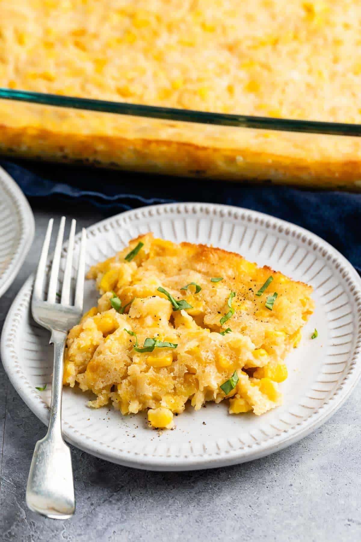 corn casserole on a grey plate with a fork.