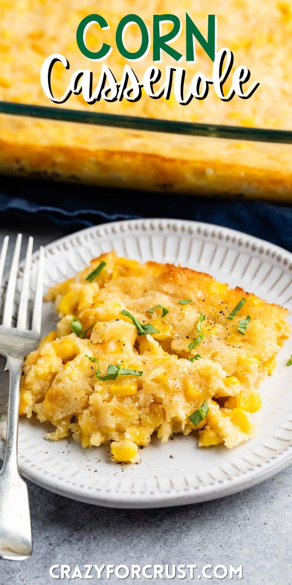 corn casserole on a grey plate with a fork with words on the image.