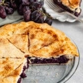 grape pie with purple grape filling in a clear pie pan.