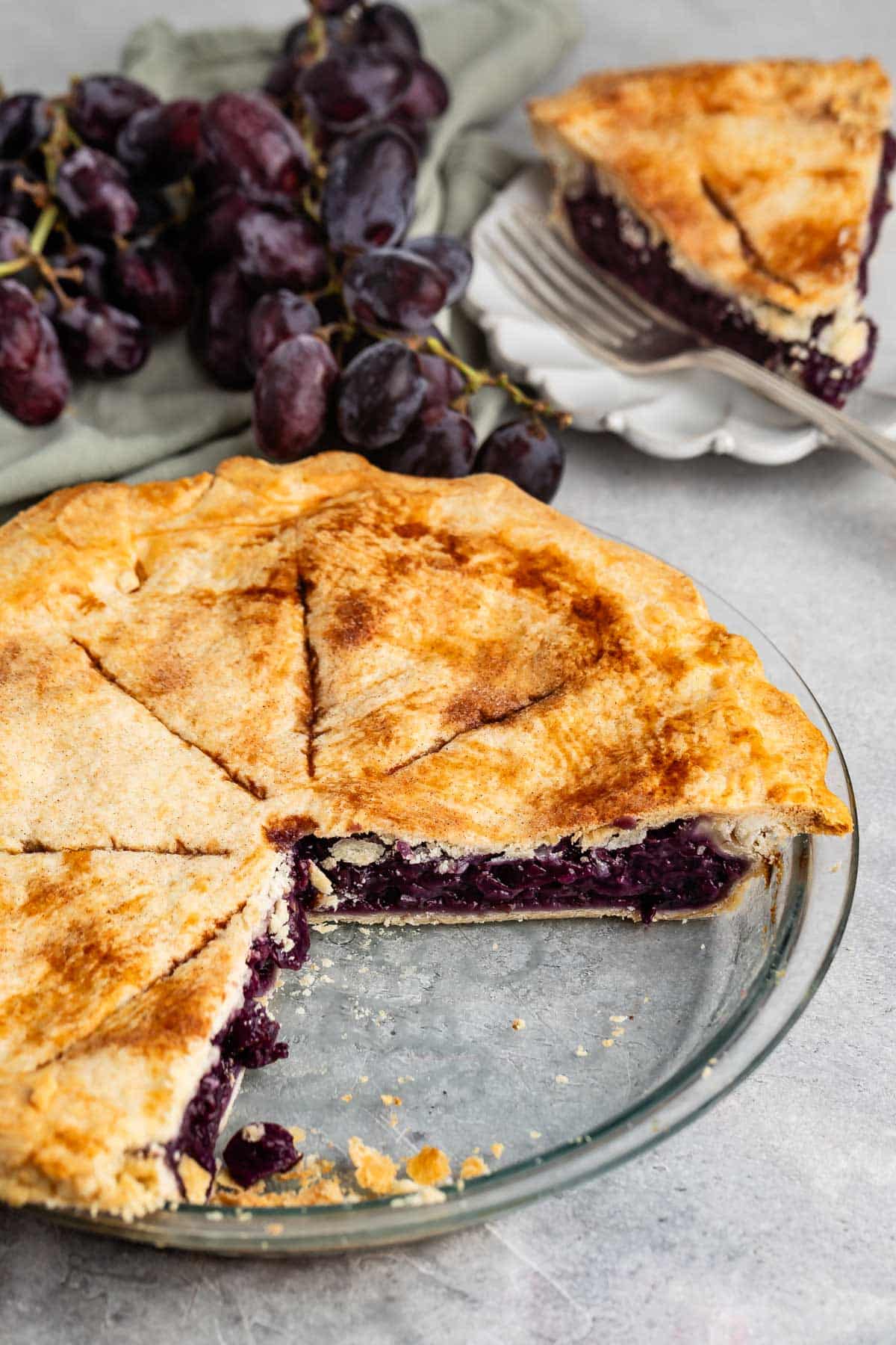 grape pie with purple grape filling in a clear pie pan.