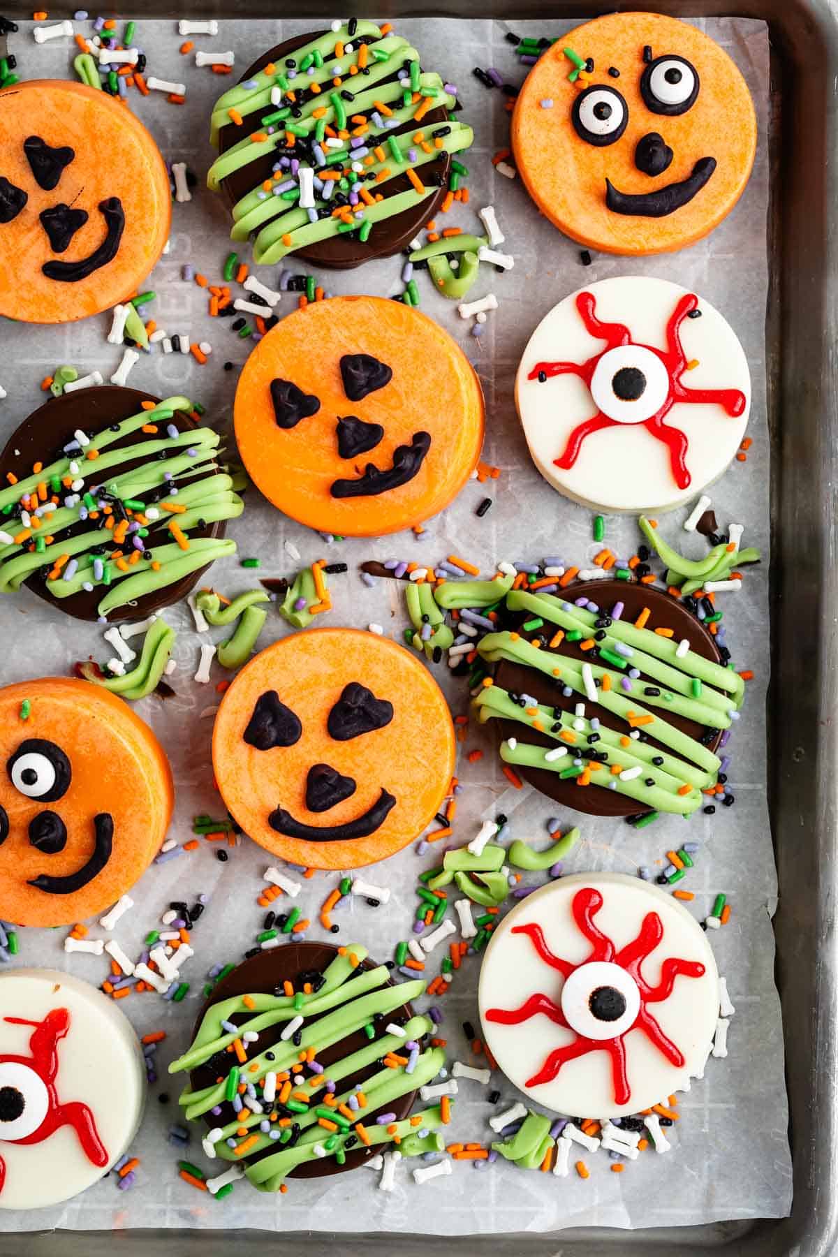 Oreos covered in different colored chocolate forming pumpkins and eyes for halloween.