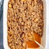 apple crisp in a white dish with a spoon.