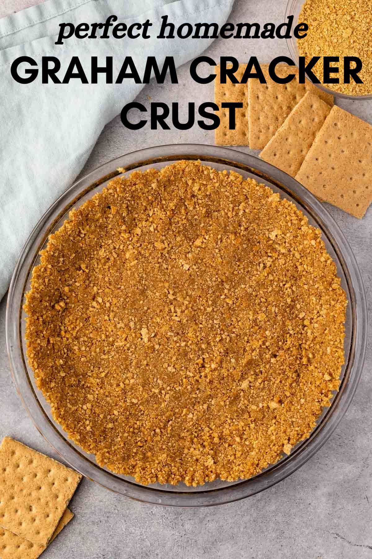 Overhead view of a glass pie dish filled with a homemade graham cracker crust, surrounded by whole graham crackers and a light blue napkin. Text at the top reads perfect homemade GRAHAM CRACKER CRUST.