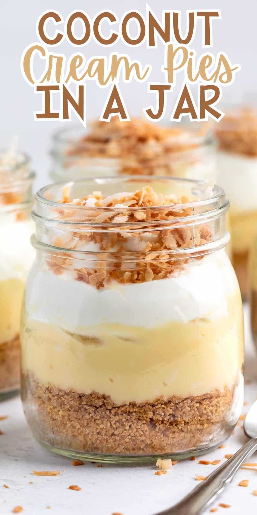 Four jars filled with layered coconut cream pie, featuring a crust, cream filling, whipped topping, and toasted coconut flakes on top. Text at the top reads Coconut Cream Pies in a Jar. A spoon is placed beside the jars.
