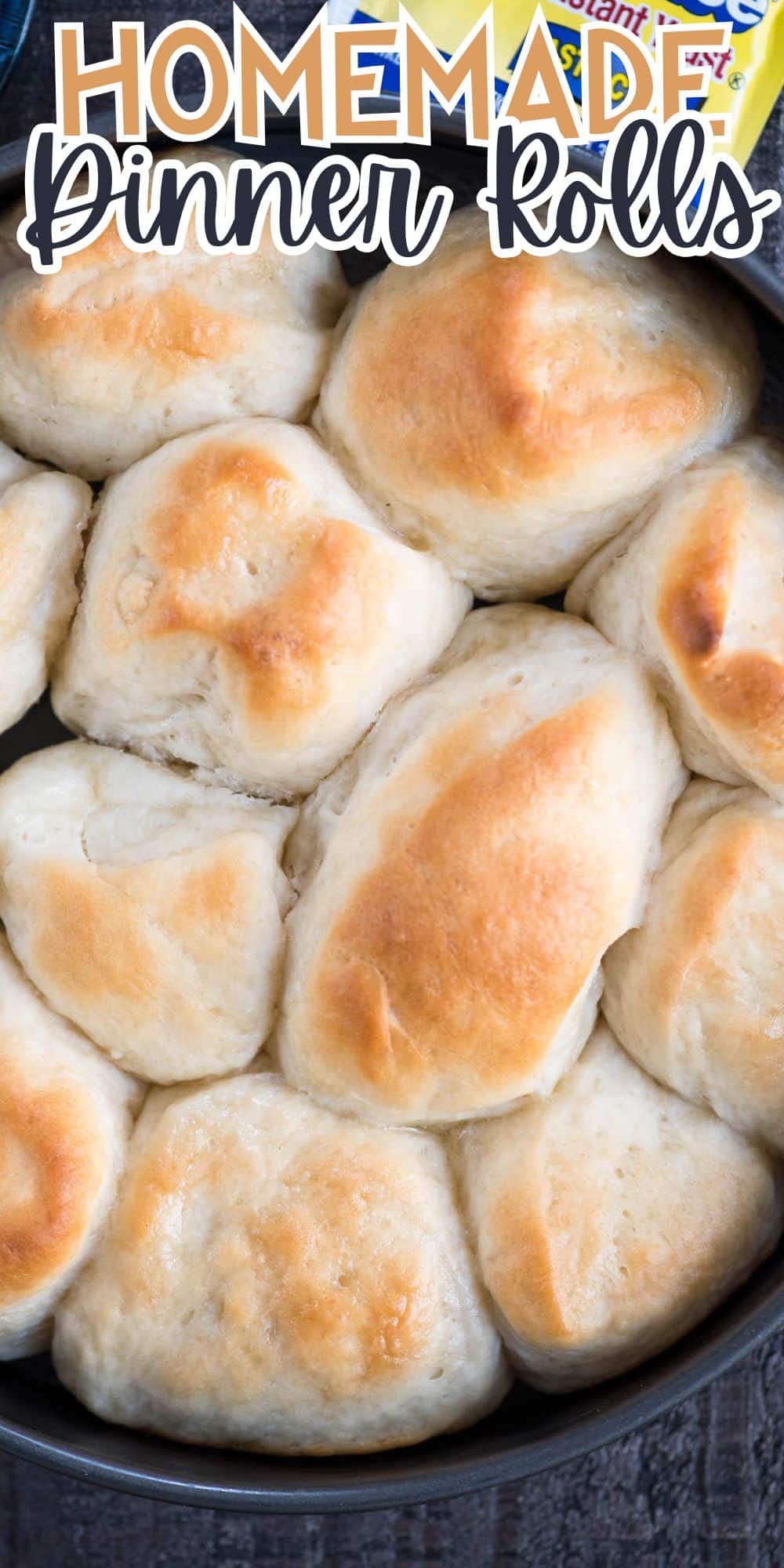 Freshly baked golden-brown dinner rolls clustered in a baking dish. A packet of instant yeast is partially visible in the background. The words Homemade Dinner Rolls are overlaid at the top.