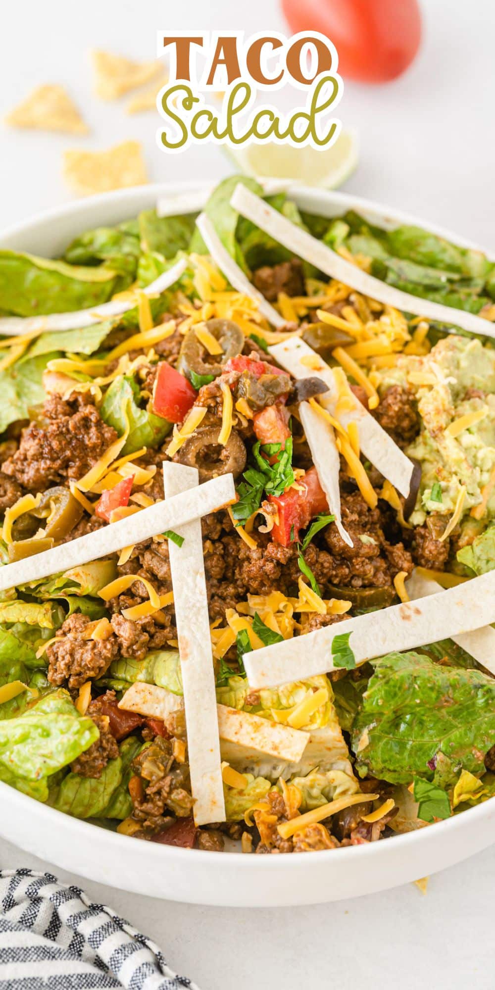 taco salad in a white bowl topped with meat and sauces with words on the image saying the name of the recipe.