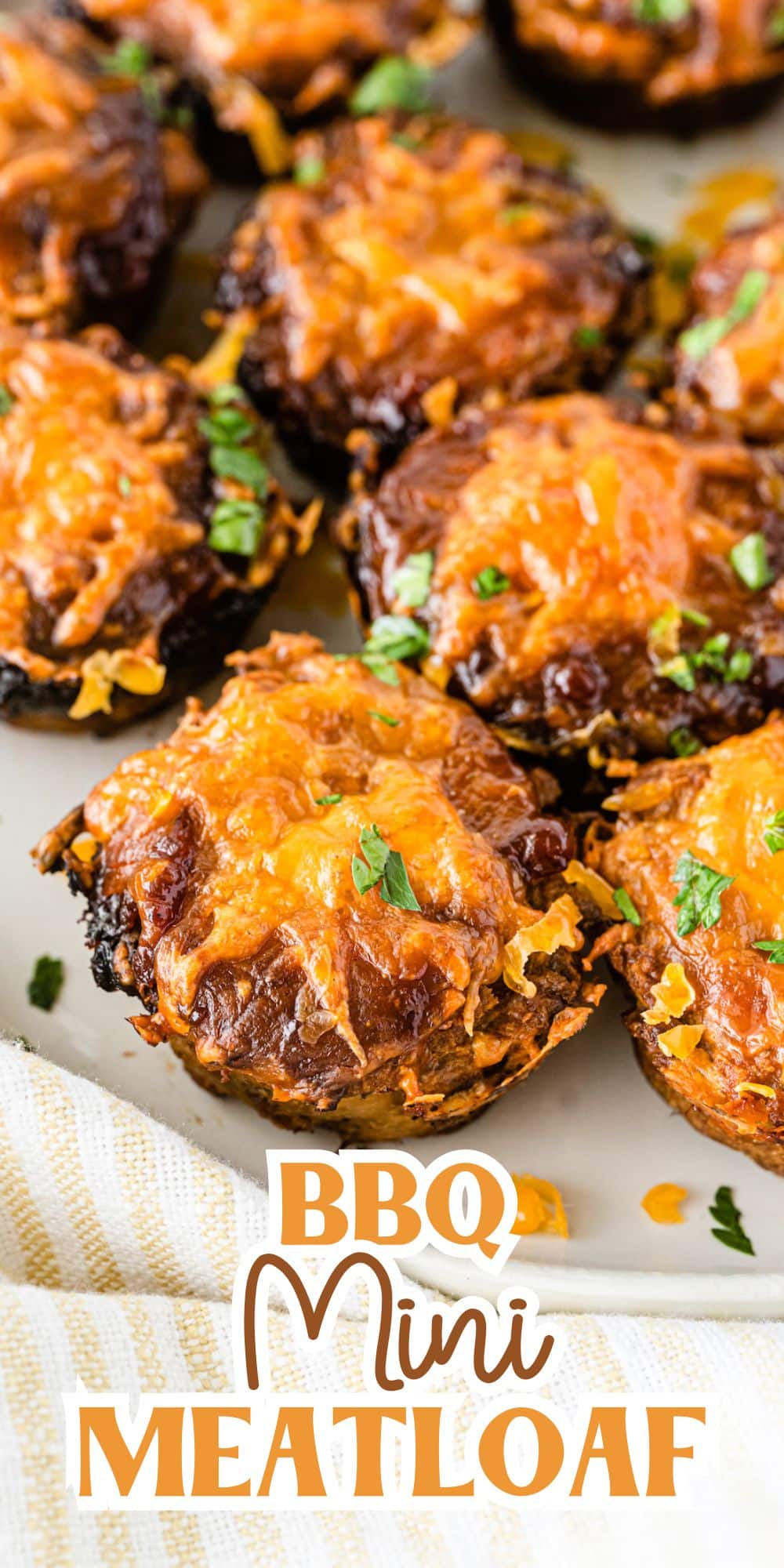 Close-up of BBQ mini meatloaves topped with melted cheese and garnished with herbs on a white plate. Text overlay at the bottom reads BBQ Mini Meatloaf.