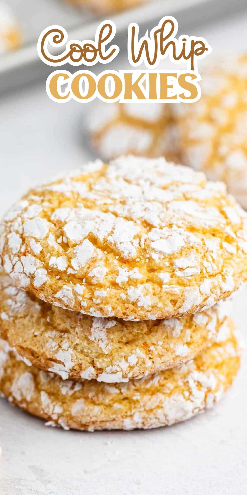 A stack of three crinkle cookies dusted with powdered sugar, labeled Cool Whip Cookies. More cookies are blurred in the background.