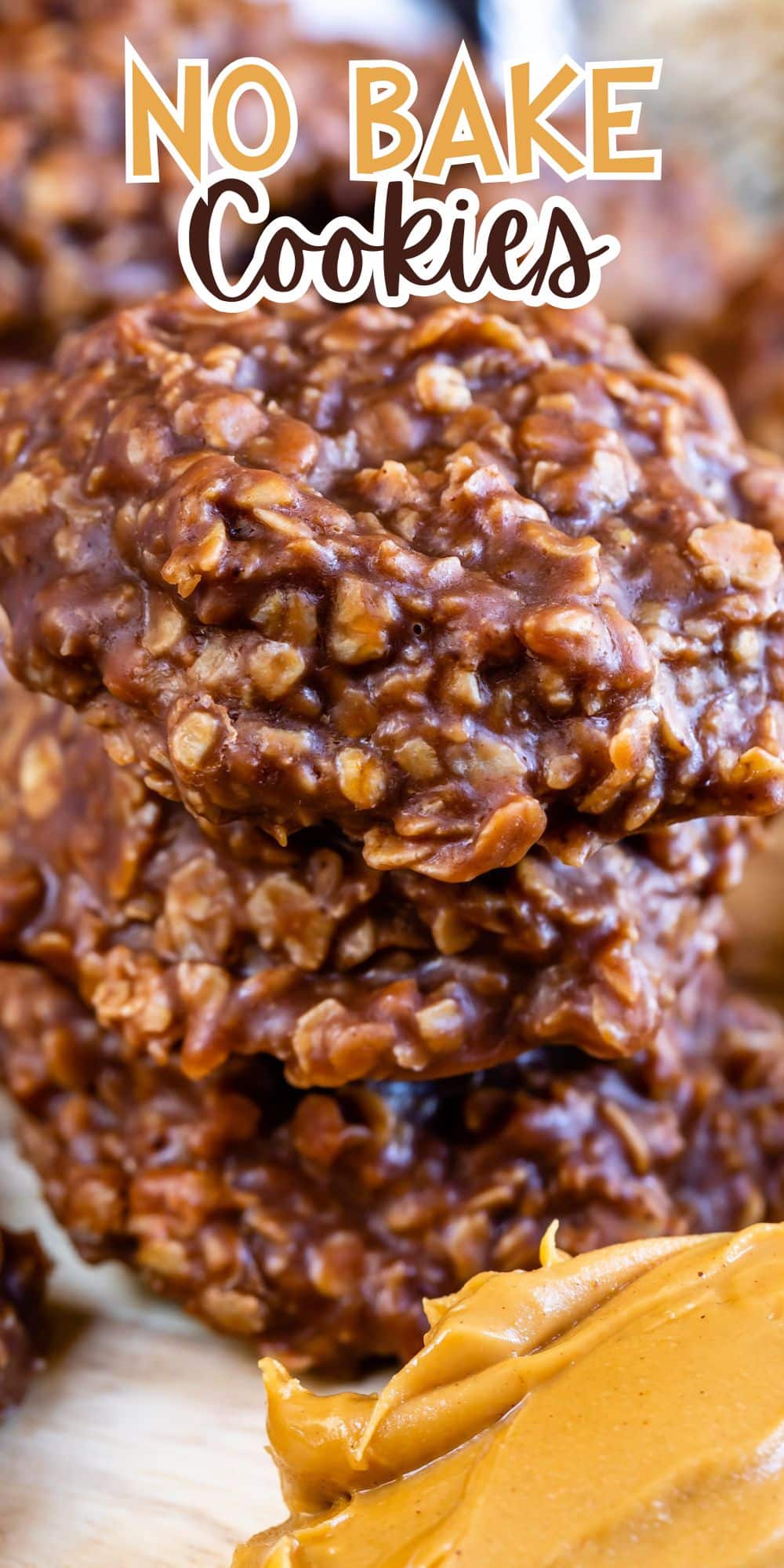 Close-up of three stacked chocolate no-bake cookies containing oats, with a spoonful of creamy peanut butter in the foreground. Text at the top reads No Bake Cookies.