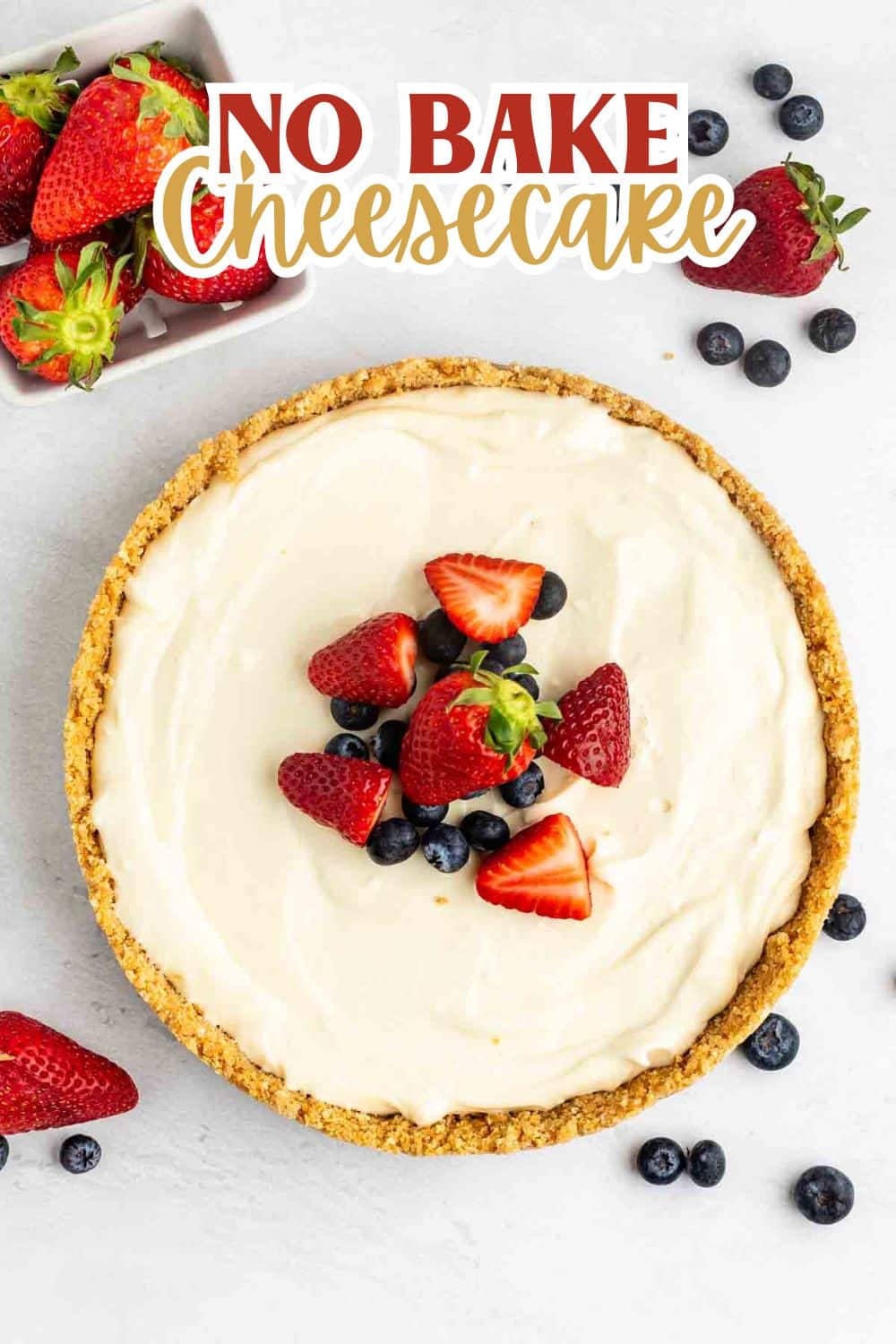 cheesecake topped with frosting, blueberries, and strawberries with the fruits also sprinkled around the cheesecake with words on the image that read the name of the recipe.