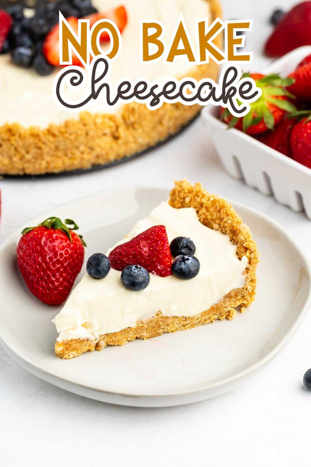 cheesecake topped with frosting, blueberries, and strawberries with the fruits also sprinkled around the cheesecake.