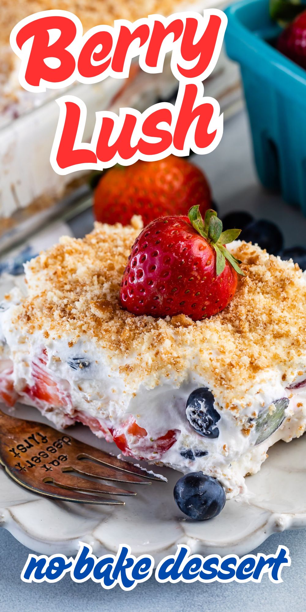A slice of berry lush dessert topped with a fresh strawberry and graham cracker crumbs, with layers of cream, blueberries, and strawberries. Decorative text reads “Berry Lush no-bake dessert.”.