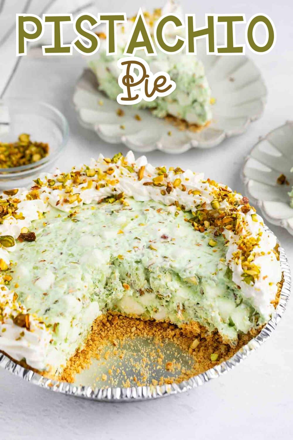 A creamy pistachio pie with a graham cracker crust, topped with whipped cream and chopped pistachios, is shown with a slice missing. The words PISTACHIO Pie appear at the top of the image.