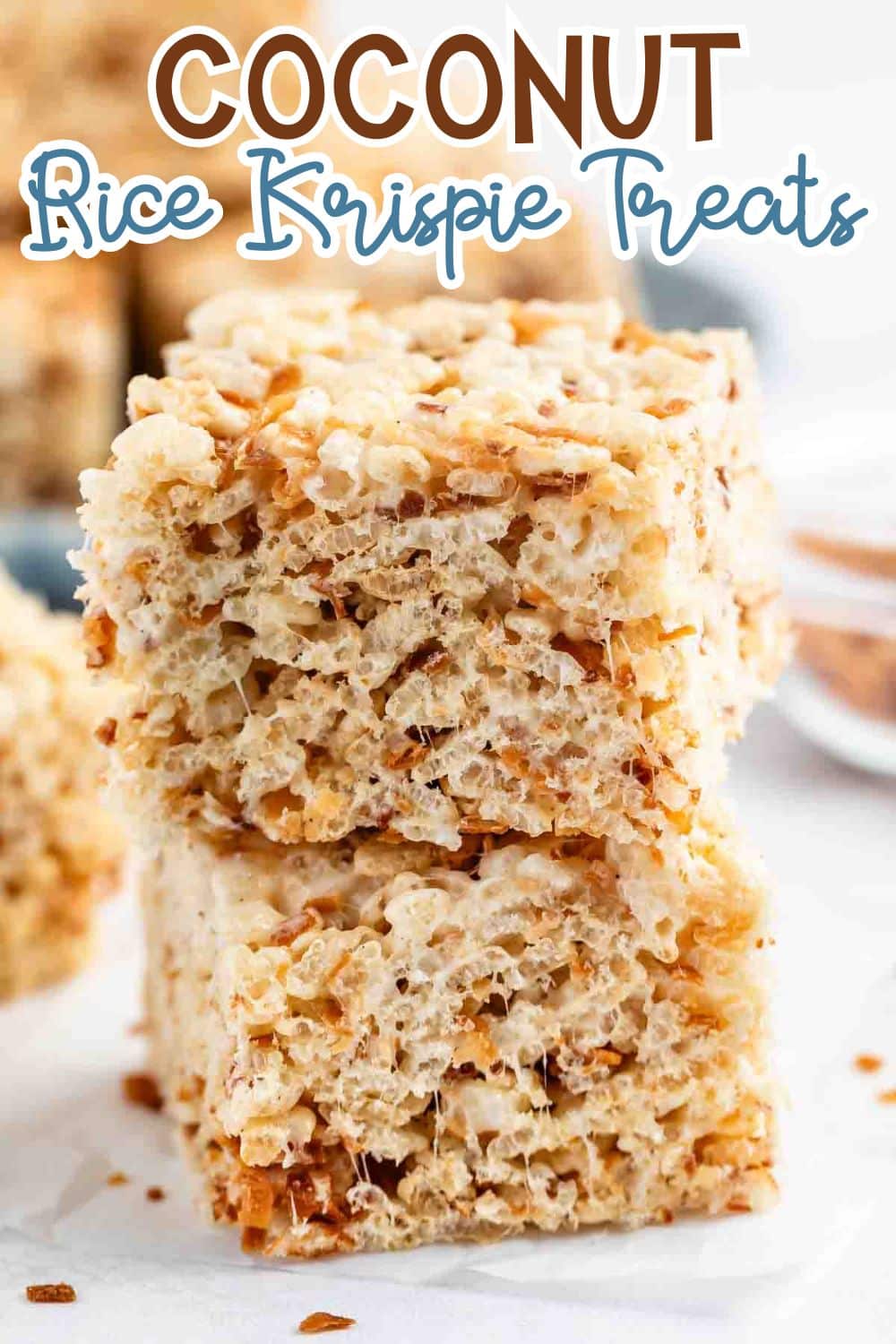 Two coconut rice krispie treats stacked on top of each other, showing a chewy texture with visible toasted coconut flakes. The text Coconut Rice Krispie Treats is displayed above the treats.