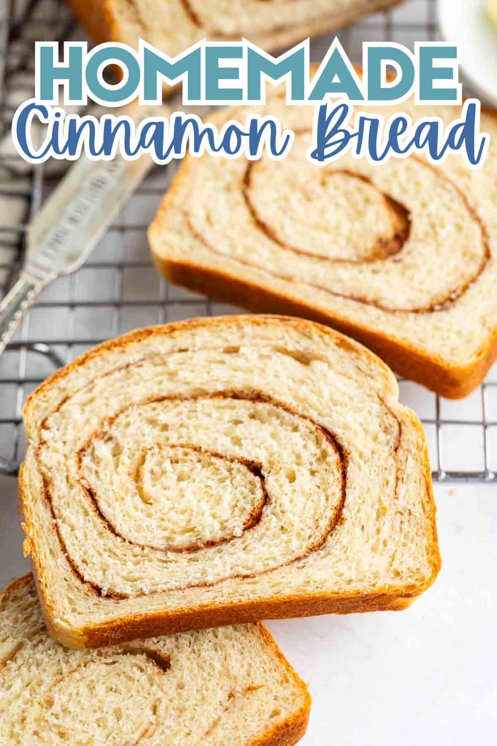 Sliced homemade cinnamon bread with visible swirls of cinnamon on a cooling rack, with a knife and plate partially visible in the background. Text overlay reads “Homemade Cinnamon Bread.”.