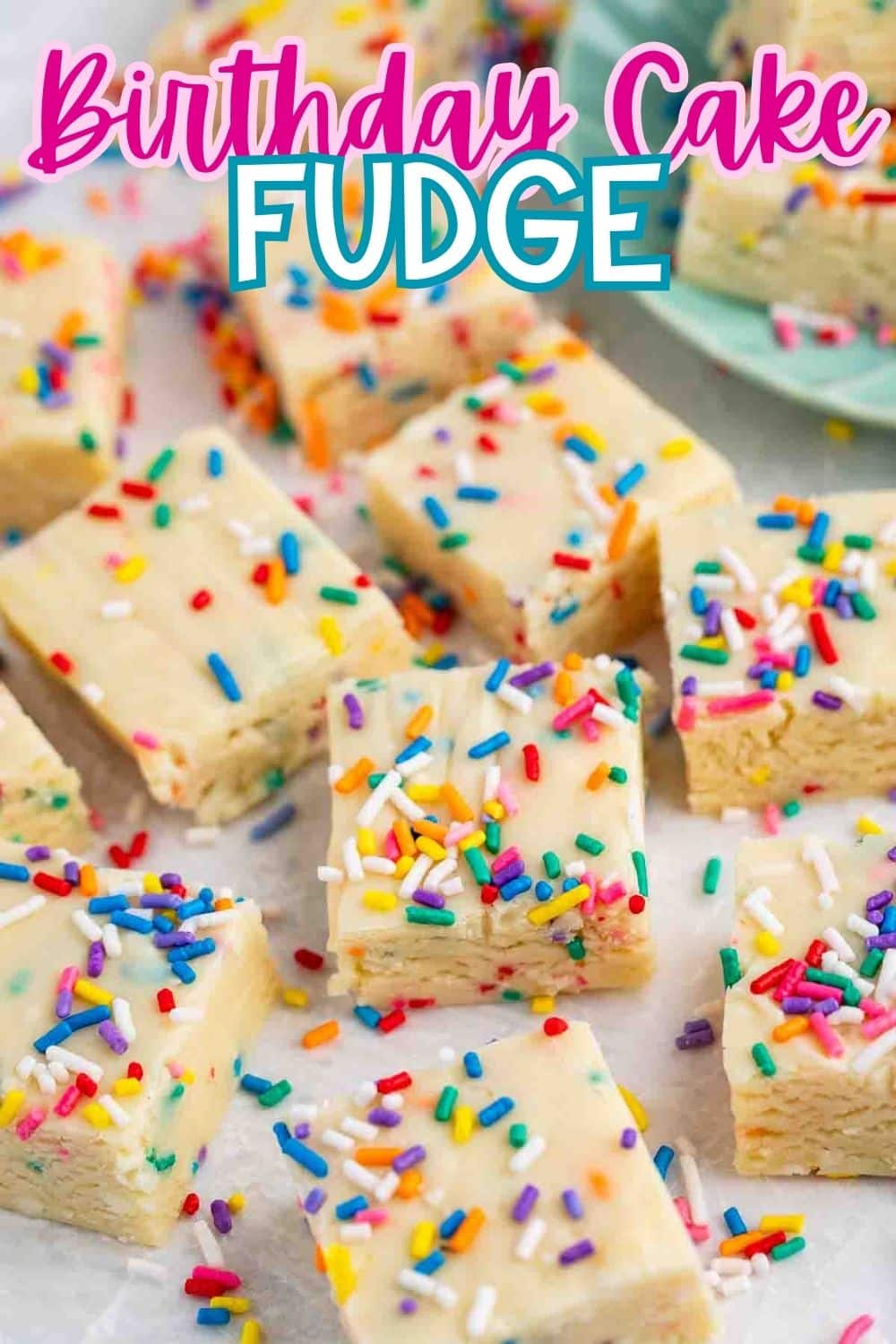 Squares of birthday cake fudge topped with colorful rainbow sprinkles are arranged on a white surface, with a plate holding more fudge pieces in the background. Text at the top reads Birthday Cake Fudge.