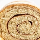 Close-up of a sliced loaf of cinnamon bread, highlighting the spiral pattern of cinnamon throughout the soft, textured crumb.