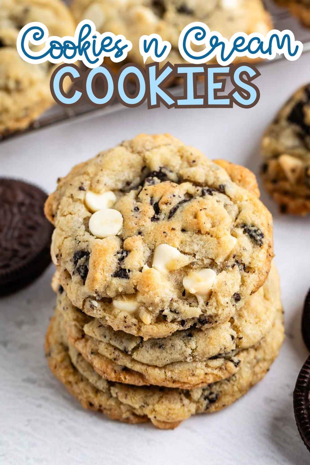 A stack of cookies and cream cookies with white chocolate chips and cookie pieces, surrounded by whole chocolate sandwich cookies, with text reading “Cookies n Cream COOKIES” at the top.