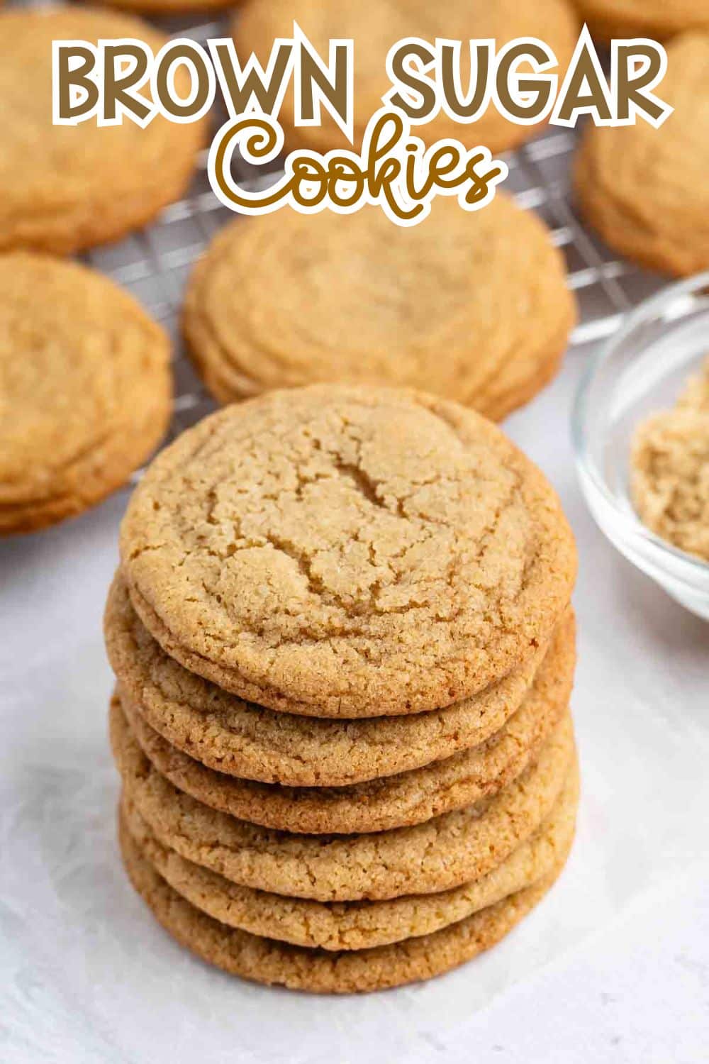 A stack of brown sugar cookies sits in the foreground, with more cookies cooling on a wire rack and a bowl of brown sugar nearby. The text Brown Sugar Cookies is displayed at the top.