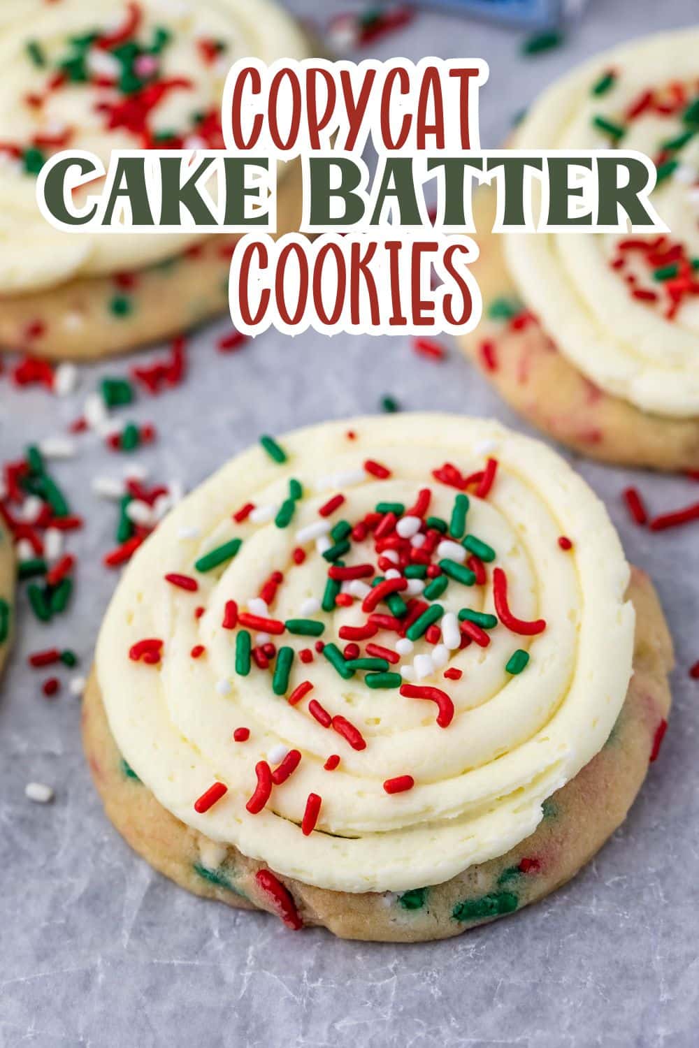 A close-up of cookies with swirled frosting and red, green, and white sprinkles. Text over the image reads: Copycat Cake Batter Cookies.