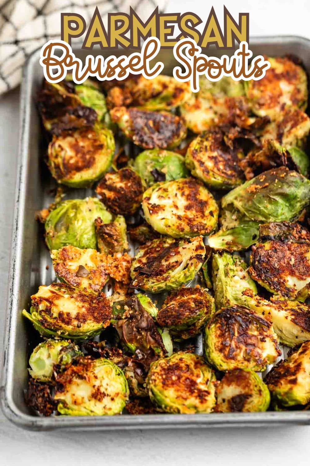 A baking tray filled with roasted Brussels sprouts coated in Parmesan cheese, displaying a crispy, golden-brown texture. The text Parmesan Brussel Sprouts is written above the tray.