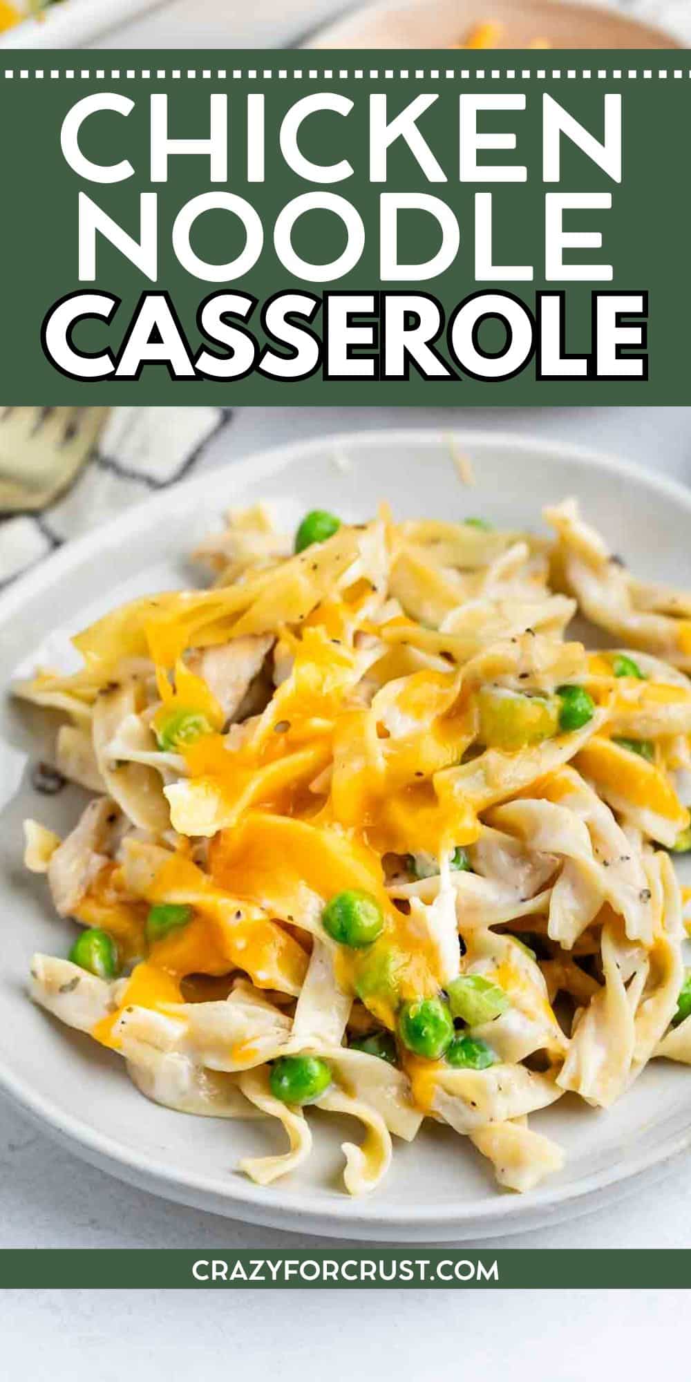 A plate of chicken noodle casserole topped with melted cheddar cheese and green peas, with a fork in the background. Text reads “Chicken Noodle Casserole” and “crazyforcrust.com.”.