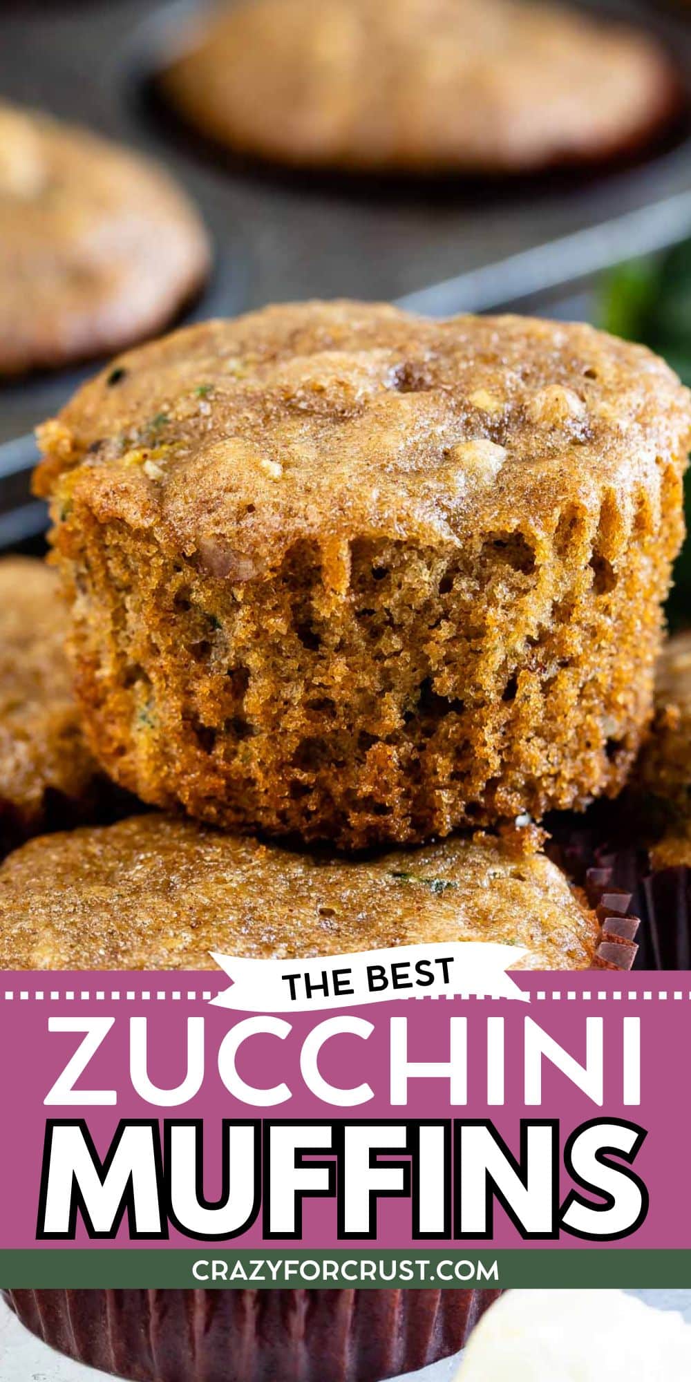 A close-up of zucchini muffins, one with a large bite taken out of it, showing a moist, tender inside. The image features the text, The Best Zucchini Muffins and the website crazyforcrust.com.