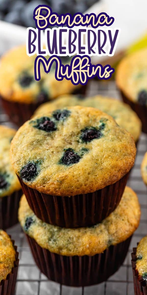 Two banana blueberry muffins stacked on top of each other on a cooling rack, with more muffins in the background. Purple text above reads Banana Blueberry Muffins.