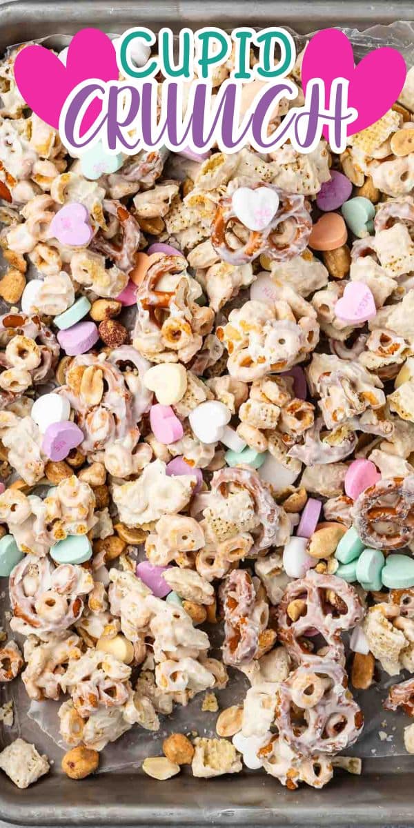 Tray of Cupid Crunch snack mix with pretzels, cereal, peanuts, heart-shaped candies, and pink and purple candy pieces, all coated in a white glaze. A colorful “Cupid Crunch” label is at the top with pink hearts.