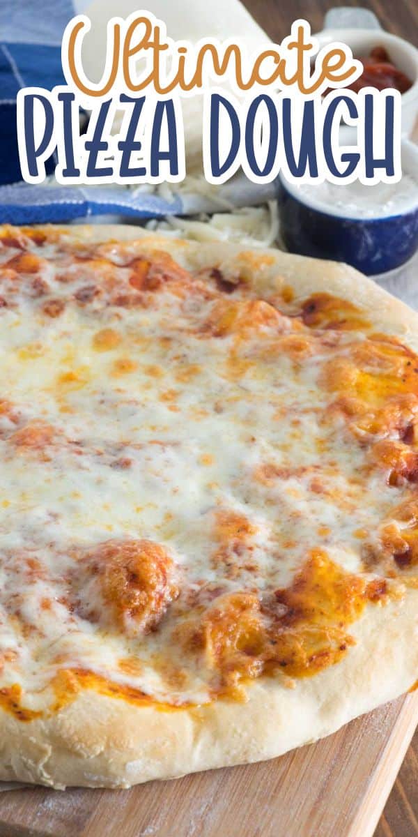 A cheese pizza with a golden, bubbly crust sits on a wooden surface. In the background are blue measuring cups and shredded cheese. Text at the top reads, “Ultimate Pizza Dough.”.
