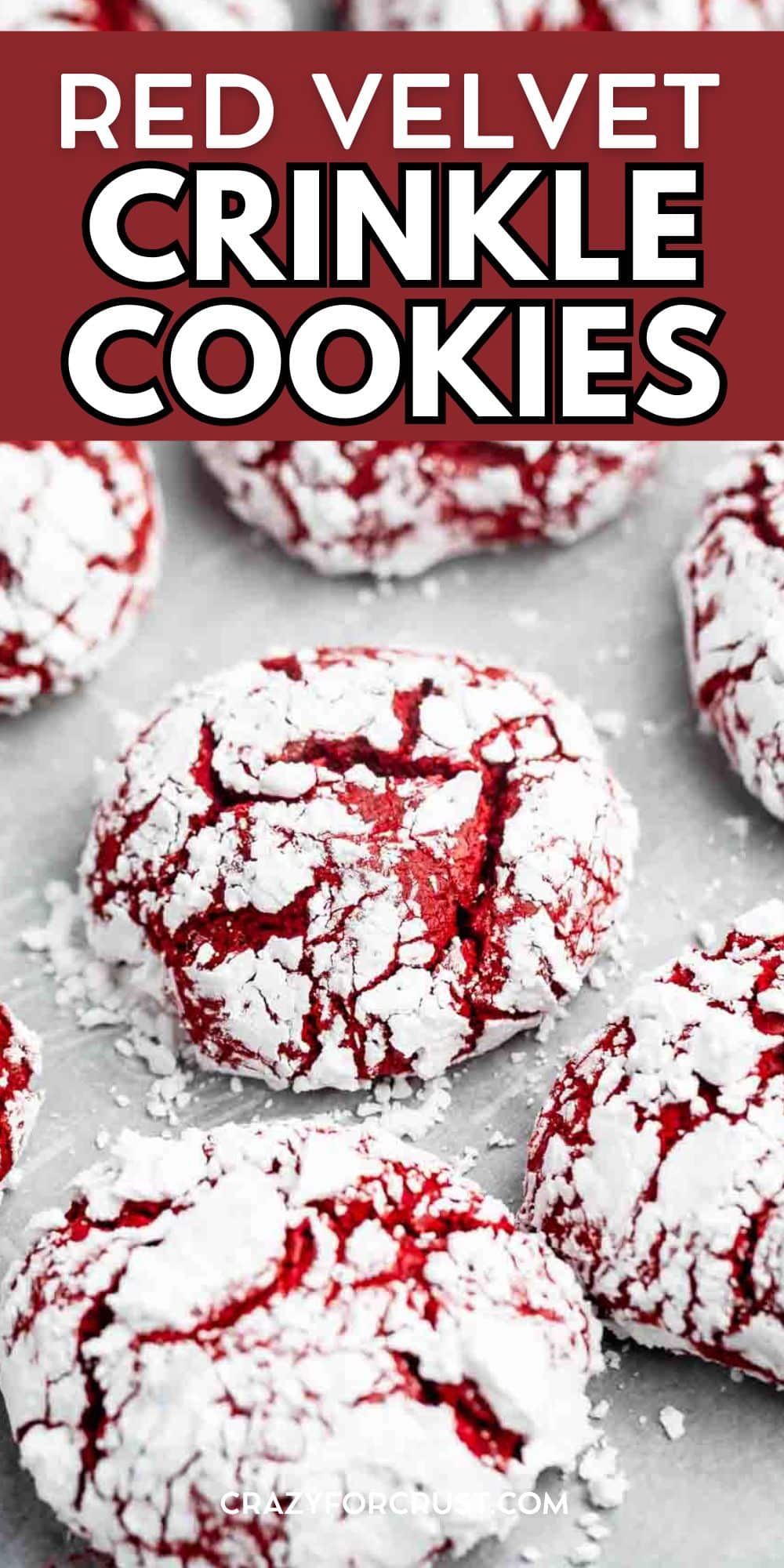 Red velvet crinkle cookies covered in powdered sugar, with cracks revealing the vibrant red interior, arranged on a light surface. Text at the top reads Red Velvet Crinkle Cookies.