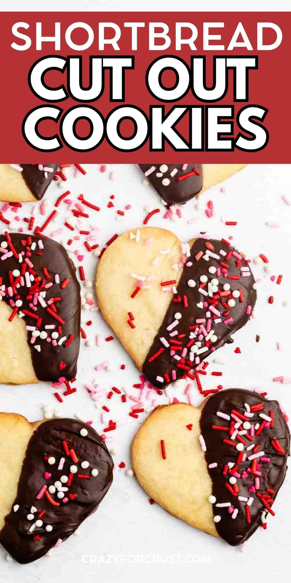 Heart-shaped shortbread cookies, half-dipped in chocolate and topped with red, pink, and white sprinkles, are arranged on a white surface. Text above reads, Shortbread Cut Out Cookies.