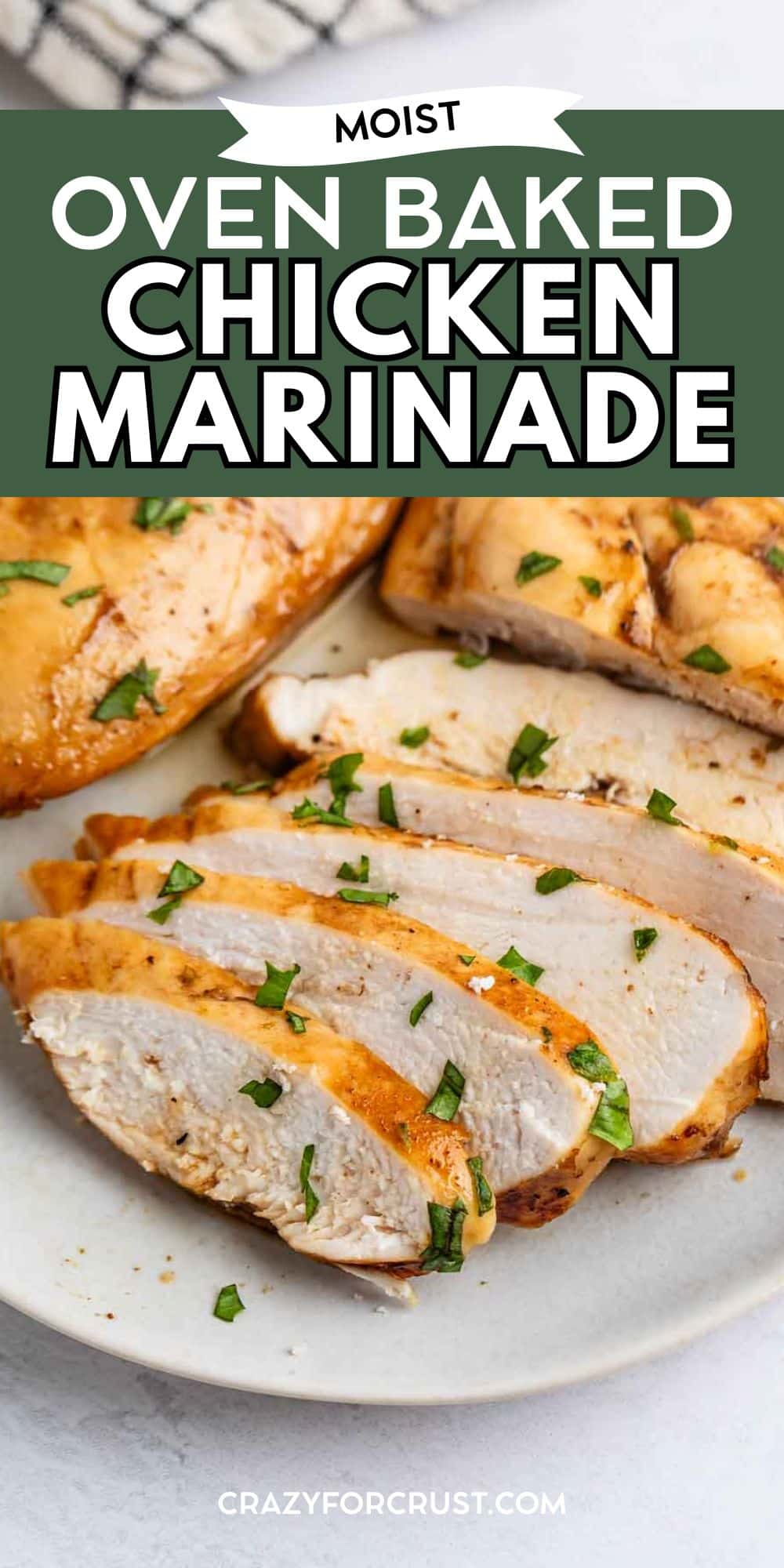 Sliced oven-baked chicken breast garnished with chopped herbs on a white plate, with bold text reading Moist Oven Baked Chicken Marinade above the dish.