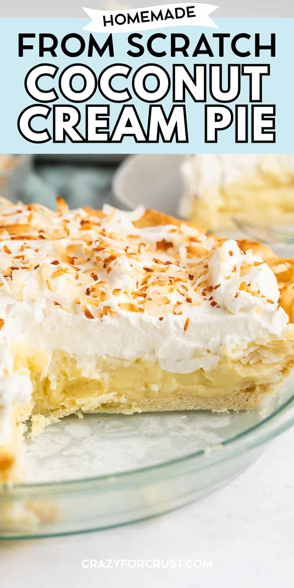 A homemade coconut cream pie in a glass dish, topped with whipped cream and toasted coconut flakes, with a slice missing to reveal the creamy filling and flaky crust.