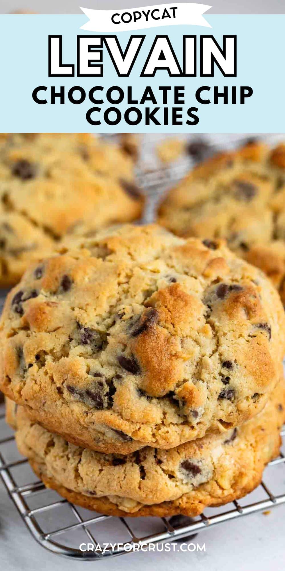 A close-up of thick, golden-brown chocolate chip cookies stacked on a cooling rack, with visible chocolate chips and a slightly crumbly texture. Text above reads “Copycat Levain Chocolate Chip Cookies.”.