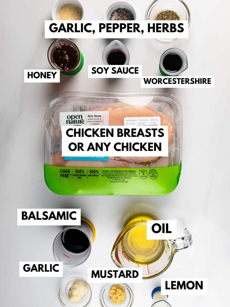 A flat lay of oven baked chicken breasts in packaging surrounded by labeled bowls of garlic, pepper, herbs, honey, soy sauce, Worcestershire, balsamic, oil, mustard, and lemon on a white background.