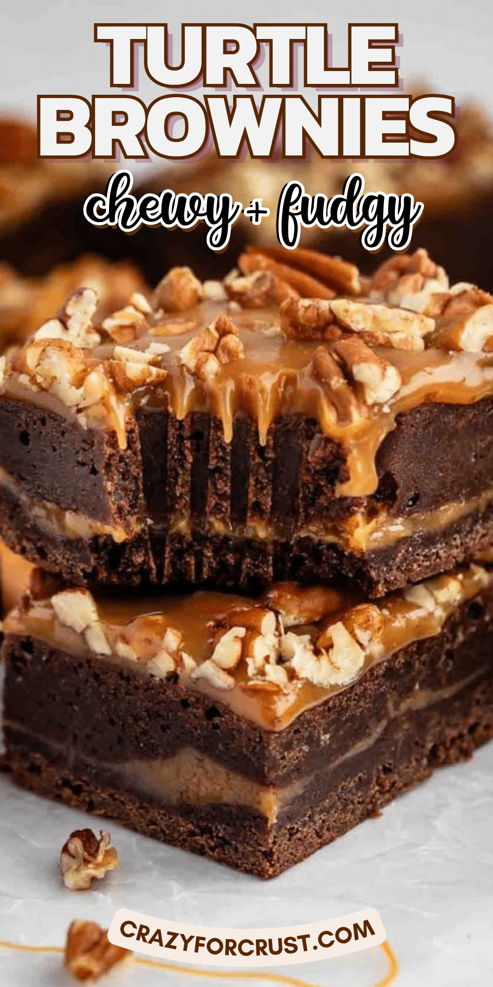 A close-up of chewy, fudgy turtle brownies topped with caramel and chopped pecans, stacked on parchment paper. The brownies have a rich, chocolatey interior and a gooey caramel layer. Text reads: Turtle Brownies. Chewy + fudgy.