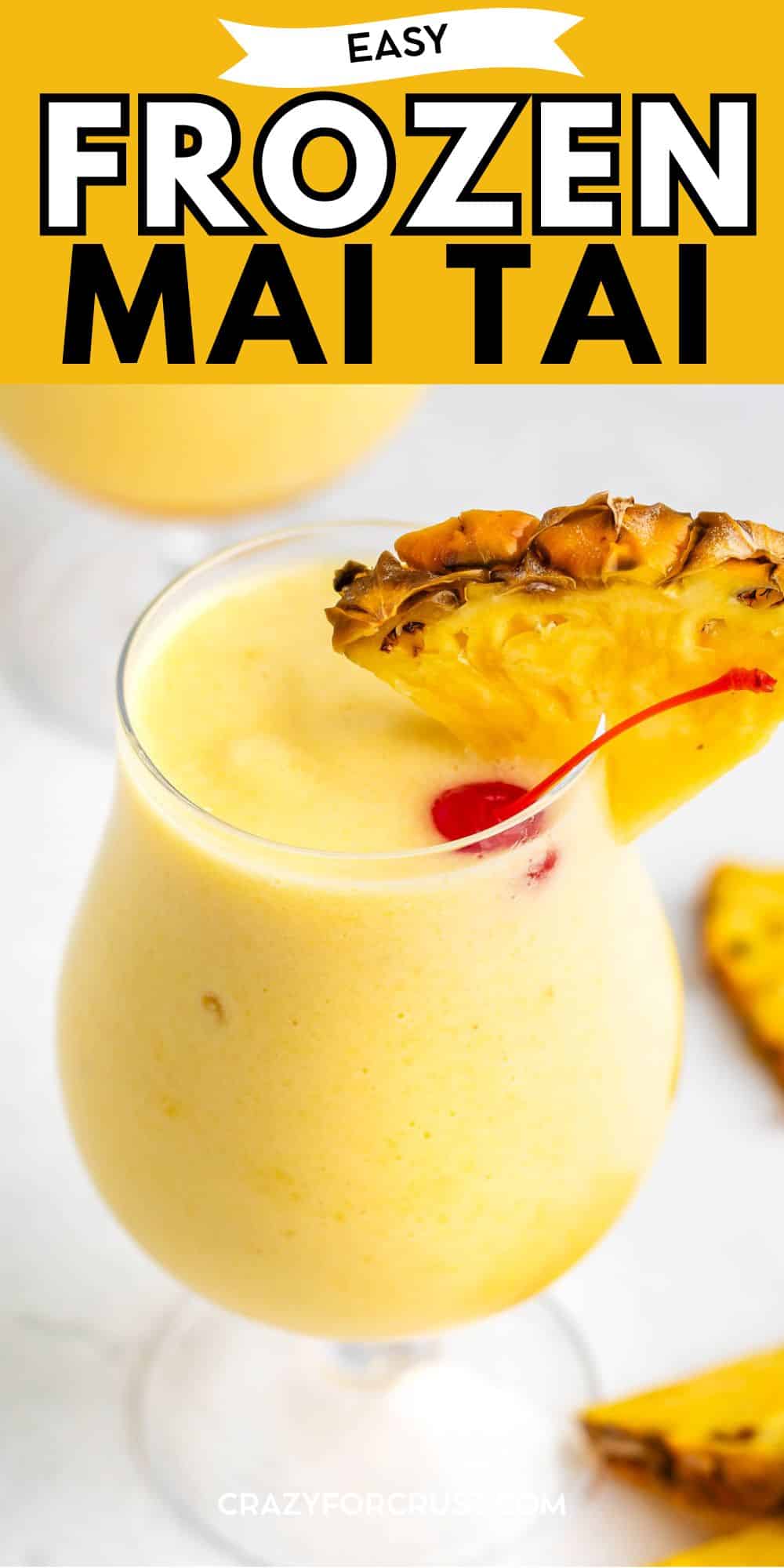A glass of frozen mai tai garnished with a pineapple wedge and cherry sits on a white surface, with pineapple slices in the background. The top of the image has text reading Easy Frozen Mai Tai.