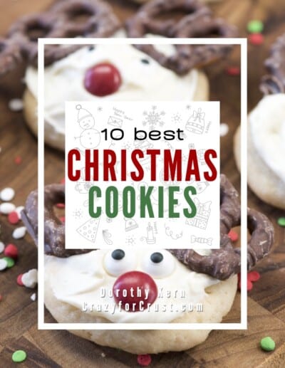 Close-up of reindeer-shaped Christmas cookies with chocolate pretzel antlers, candy eyes, and red noses on a wooden surface. Overlaid text reads 10 Best Christmas Cookies by Dorothy Kern.